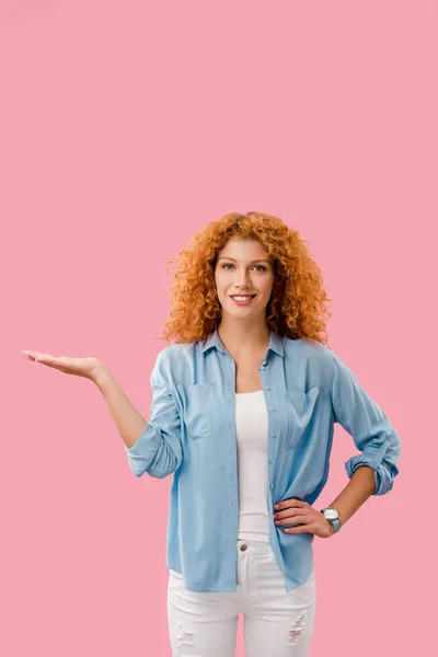 Aantrekkelijke Redhead Vrouw Presenteren Iets Geïsoleerd Roze — Stockfoto