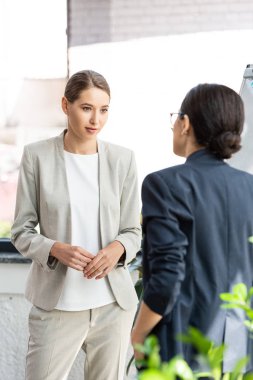 two colleagues in formal wear looking at each other in office clipart