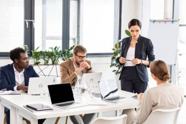 ofiste konferans sırasında dizüstü bilgisayarlar ile masada çok ırklı işadamları