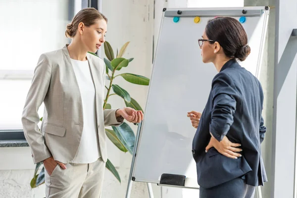 Dwie Bizneswomen Formalnych Nosić Stojący Pobliżu Flipchart Biurze — Zdjęcie stockowe