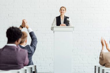 konferans salonunda konferans sırasında ayakta ve gülümseyen çekici iş kadını