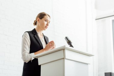 konferans salonunda konferans sırasında ayakta ve uzağa bakan çekici iş kadını