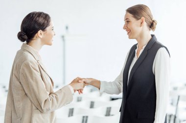 konferans salonunda el sıkışma resmi giyim iki çekici meslektaşları