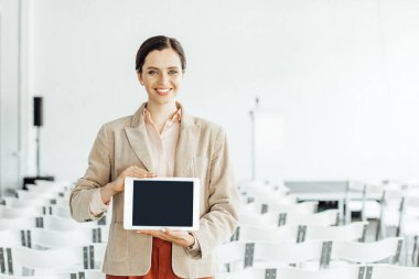 resmi giyim gülümseyen ve dijital tablet tutan çekici iş kadını 