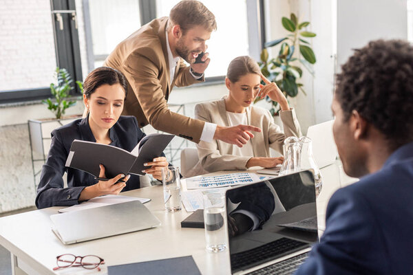 multiethnic businesspeople in formal wear at table during conference in office