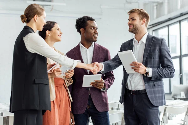 Four Multiethnic Colleagues Holding Digital Tablets Shaking Hands Conference Hall — Stock Photo, Image