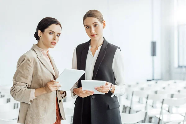 Dos Colegas Atractivos Ropa Formal Sosteniendo Tabletas Digitales Sala Conferencias — Foto de Stock