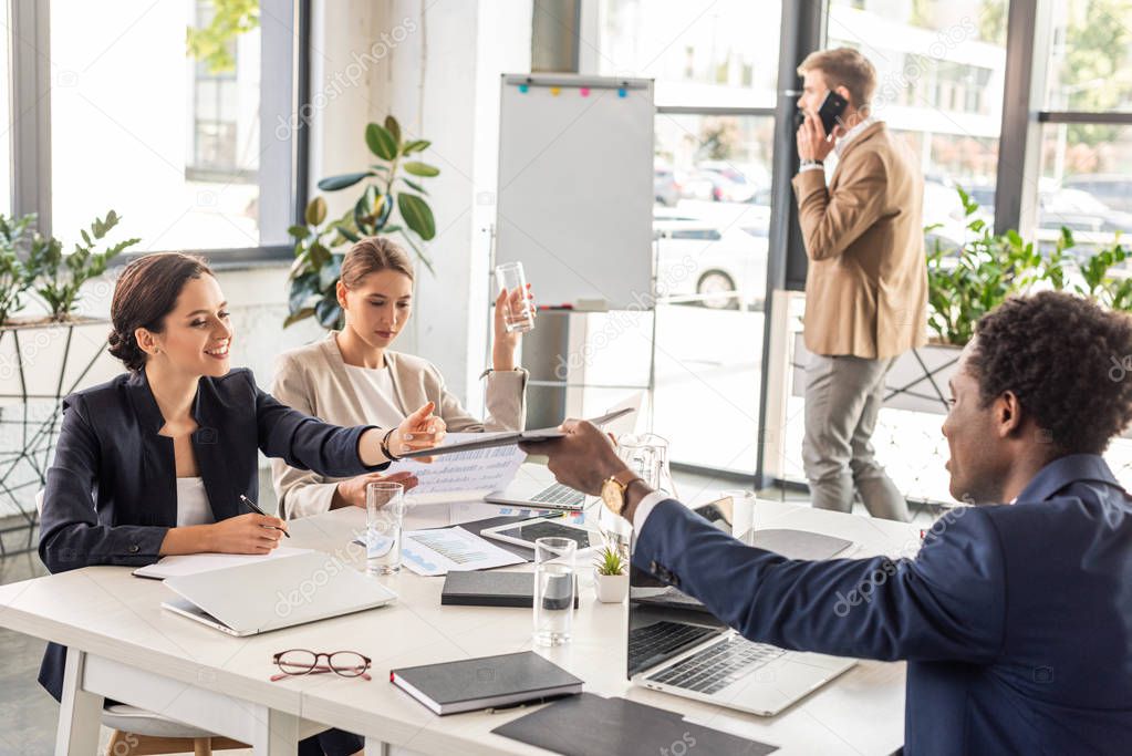 multiethnic businesspeople in formal wear at table during conference in office