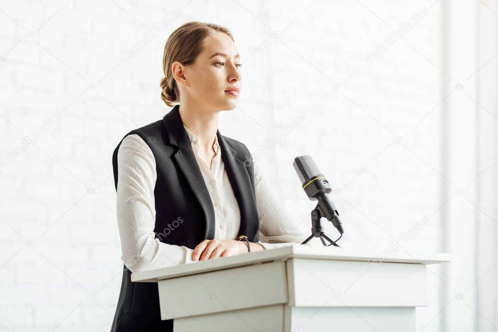 attractive businesswoman standing and looking away during conference in conference hall