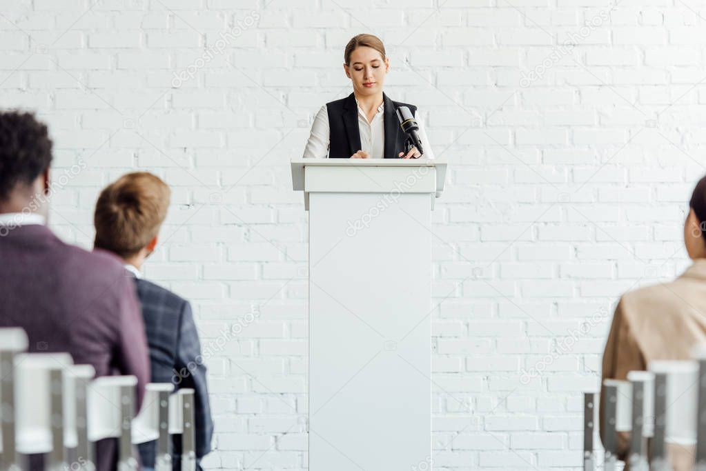 attractive businesswoman standing and talking during conference in conference hall