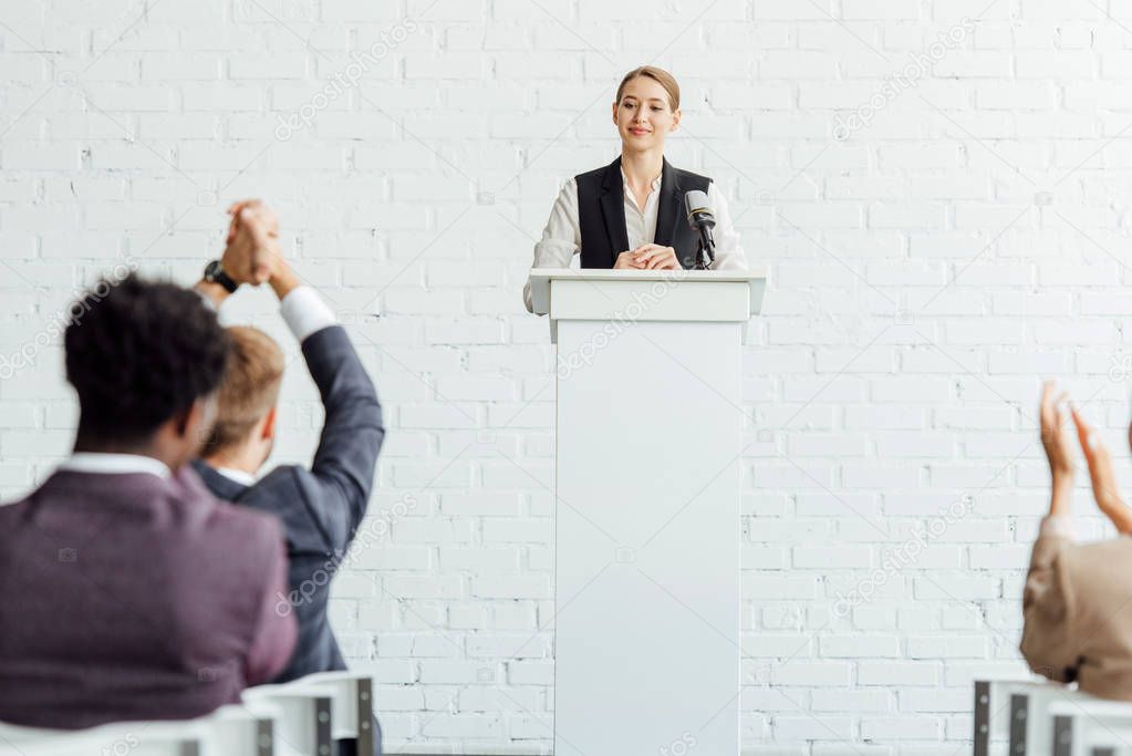attractive businesswoman standing and smiling during conference in conference hall