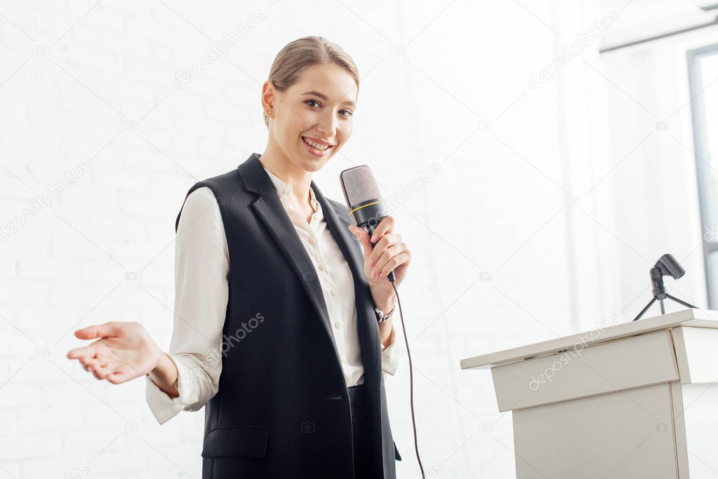 attractive businesswoman holding microphone and talking during conference in conference hall