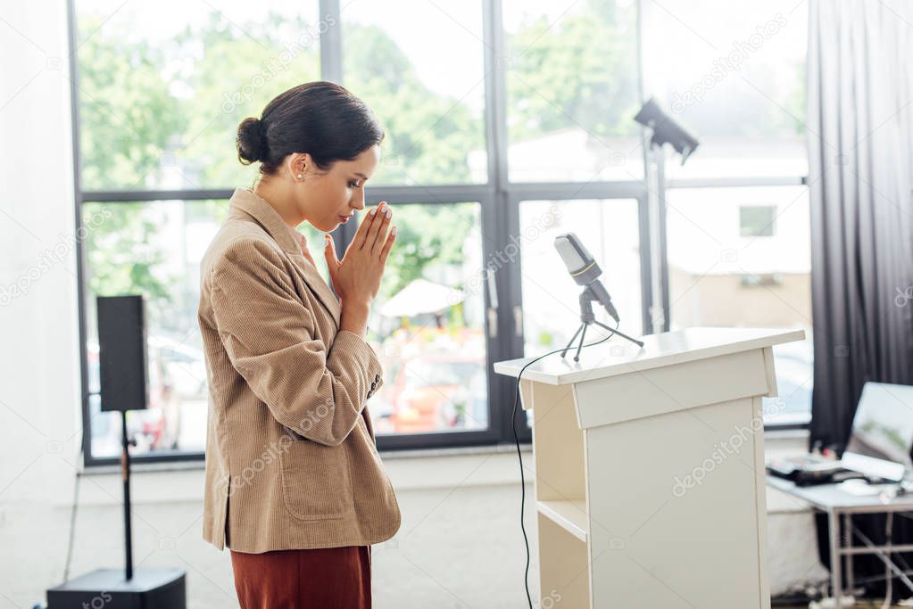 side view of attractive businesswoman praying during conference in conference hall