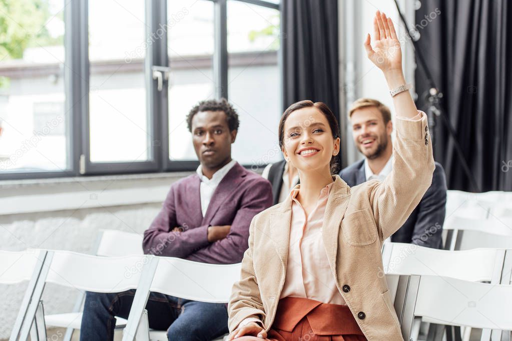 selective focus of attractive businesswoman raising hand during conference 