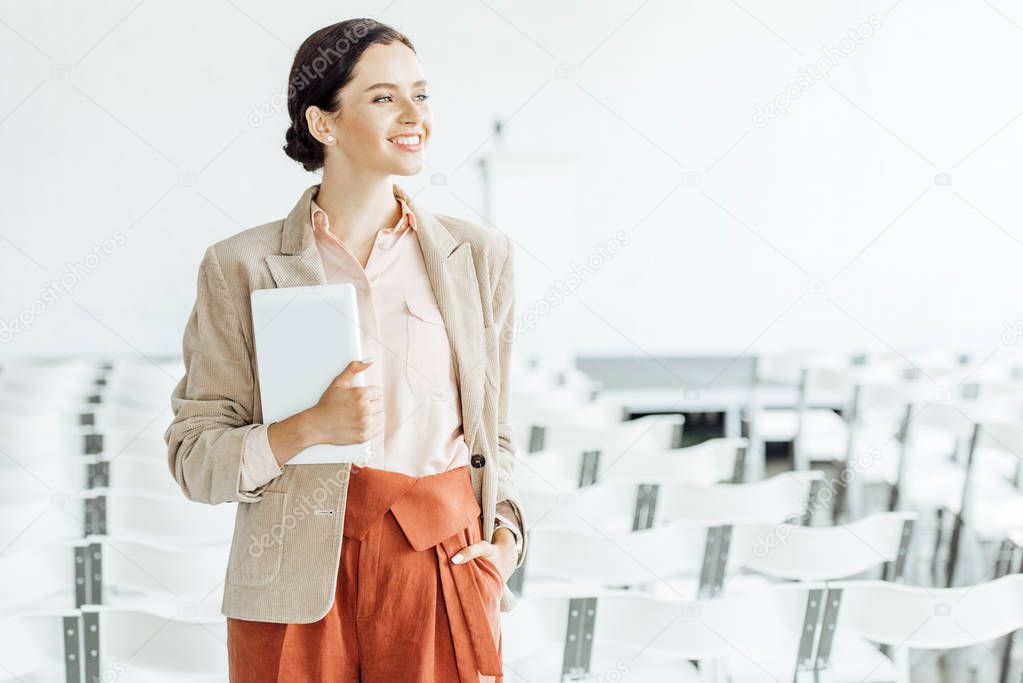 attractive businesswoman in formal wear smiling and holding digital tablet 