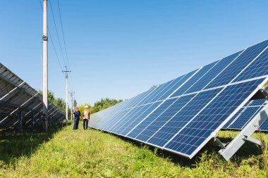 mühendis ve iş kadını güneş enerjisi pilleri yakınında yürüyüş 