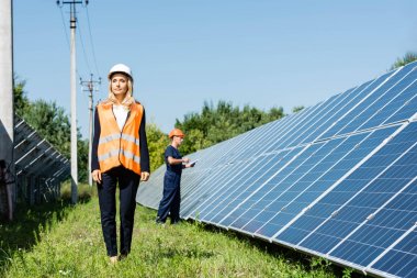 güneş enerjisi pilleri yakınında yürüyüş hardhat çekici iş kadını  