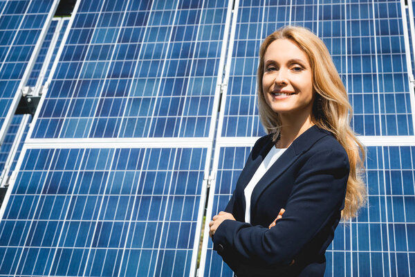 привлекательная деловая женщина со скрещенными руками улыбается и смотрит в камеру
