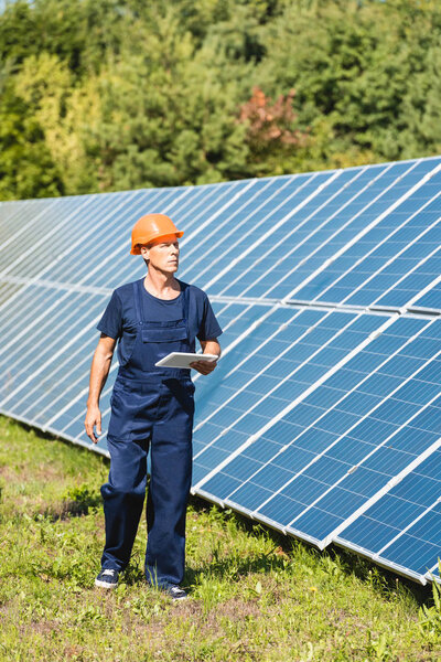 красивый инженер в комбинезоне и каскаде с цифровым планшетом
 