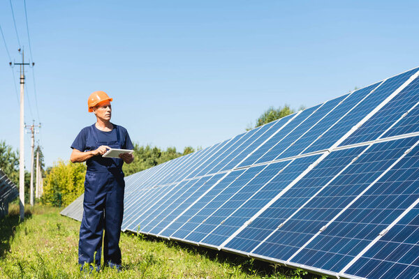 красивый инженер в комбинезоне и каскаде с цифровым планшетом
 