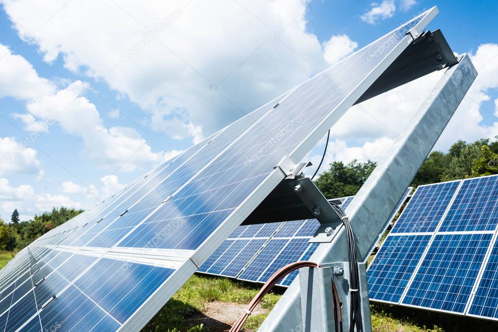 blue solar energy batteries, green grass and cloudy sky outside 