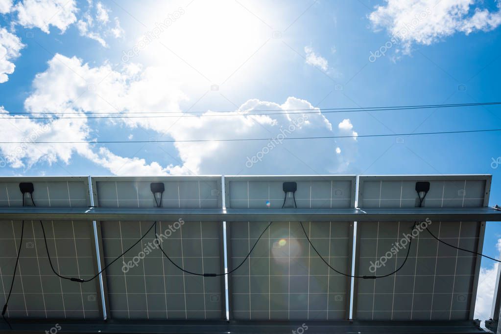 blue solar energy batteries, sun and cloudy sky outside 