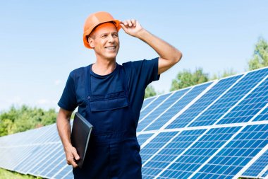 t-shirt ve turuncu hardhat gülümseyen ve klasör tutan yakışıklı mühendis 