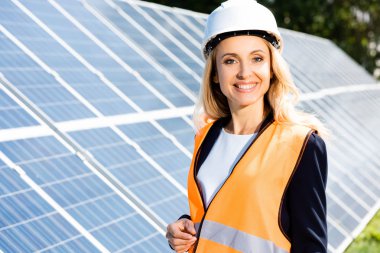 güvenlik yelek ve hardhat içinde iş kadını gülümseyerek ve kameraya bakarak 