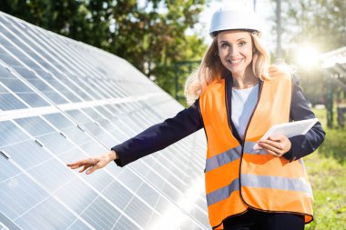 güvenlik yelek ve hardhat gülümseyen ve dijital tablet tutan iş kadını 
