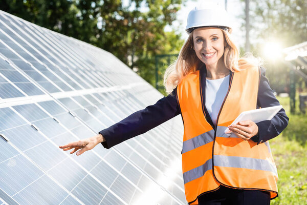 деловая женщина в спасательном жилете и каске улыбаясь и держа цифровой планшет
 