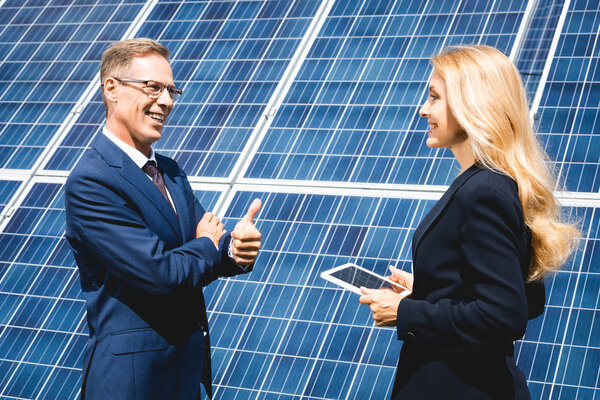 Красивый бизнесмен показывает большой палец вверх и деловая женщина держит цифровой планшет
 