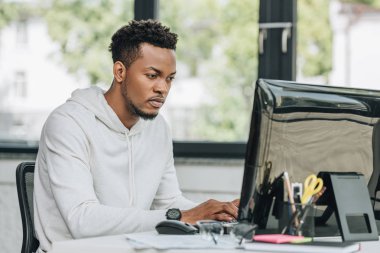 ofiste bilgisayar üzerinde çalışan konsantre afro-amerikan programcı