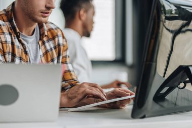 Afro-Amerikan meslektaşının yakınında ofiste çalışan programcının kırpılmış görünümü