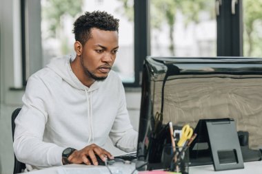 attentive african american programmer working on computer in office clipart