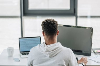 back view of african american programmer working on computers in office clipart