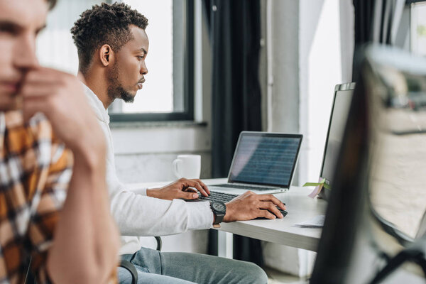 young african american programmer working on computer near colleague