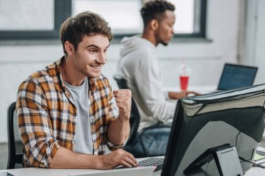 neşeli programcı afrikalı Amerikalı meslektaşın yakınında çalışırken kazanan jest gösteren