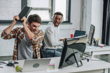 Afro-Amerikan meslektaşının yanında otururken rahatsız programcı kırma klavye seçici odak
