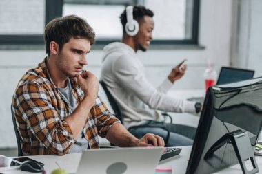 ofiste Afrikalı-Amerikalı meslektaşın yanında çalışan düşünceli programcı seçici odak