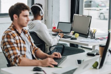 iş arkadaşı yakın işyerinde oturan kulaklık afro-amerikan programcı seçici odak