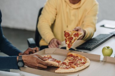 ofiste pizza yiyen iki çok kültürlü programcıların kırpılmış görünümü
