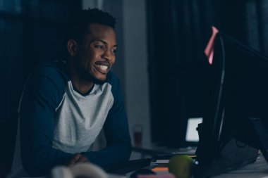 bilgisayar monitörü bakarken neşeli afrikalı amerikalı programcı gülümseyen