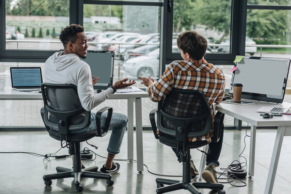 two young multicultural programmers discussing ideas while working together