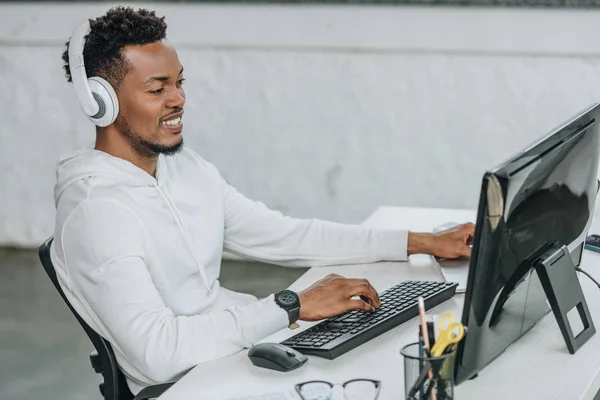 Fröhlicher Afrikanisch Amerikanischer Programmierer Sitzt Mit Kopfhörern Arbeitsplatz — Stockfoto