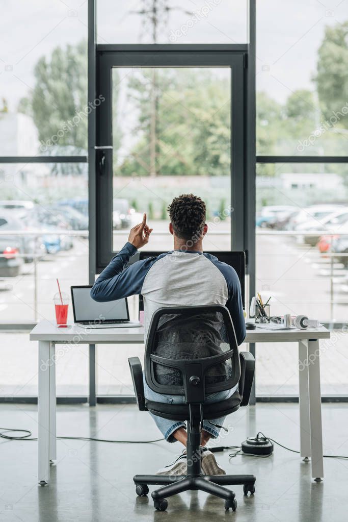 back view of young african american programmer showing idea sign while sitting at workplace in office