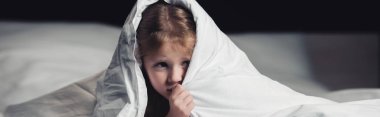 panoramic shot of scared child hiding under blanket isolated on black clipart