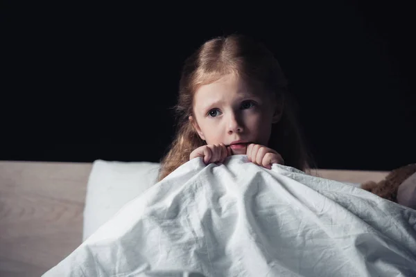 Scared Child Looking Away While Sitting Bedding Dark Bedroom Isolated — Stock Photo, Image