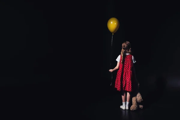 Achteraanzicht Van Depressief Kind Met Gele Ballon Teddybeer Geïsoleerd Zwart — Stockfoto