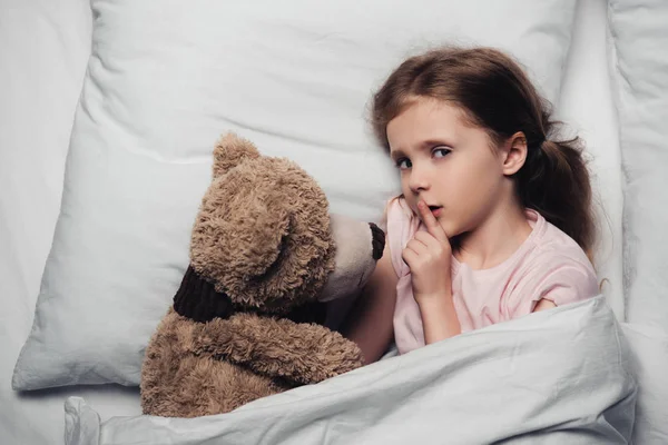 베어와 침대에 누워있는 사인을 보여주고 카메라를 보고있는 무서운 아이의 상단보기 — 스톡 사진
