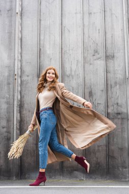 çekici ve gülümseyen kadın ceket çivi tutan ve uzağa bakarak 